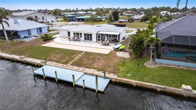 back of house featuring a residential view, a lawn, and a water view