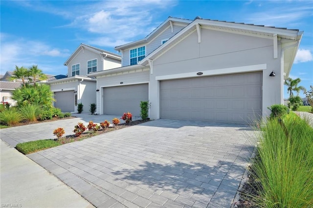 view of front facade with decorative driveway, a garage, and stucco siding