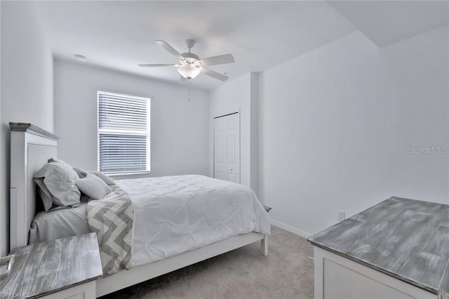 bedroom featuring baseboards, light colored carpet, a closet, and ceiling fan