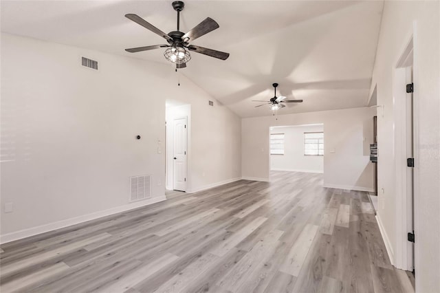 spare room featuring visible vents, baseboards, light wood-style flooring, and vaulted ceiling