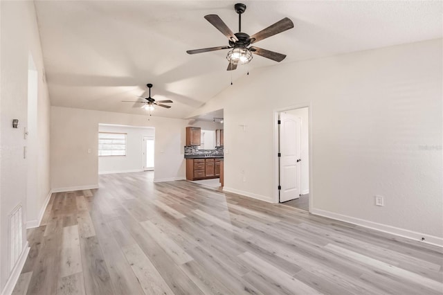 unfurnished living room with visible vents, light wood finished floors, baseboards, ceiling fan, and vaulted ceiling