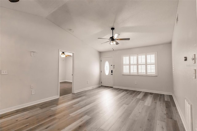 interior space with visible vents, baseboards, lofted ceiling, wood finished floors, and a ceiling fan