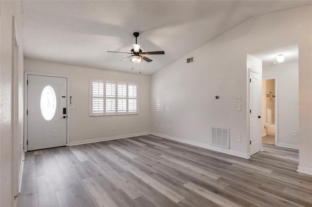 entryway with visible vents, lofted ceiling, wood finished floors, baseboards, and ceiling fan