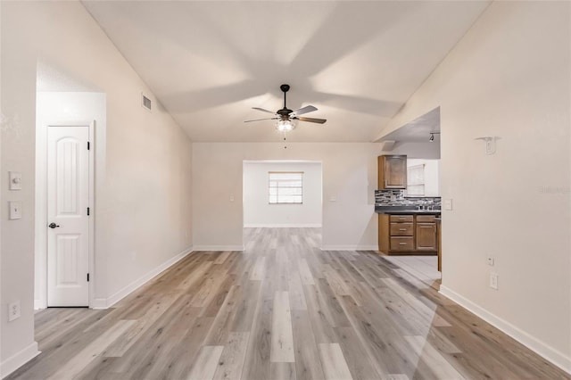 unfurnished living room with baseboards, visible vents, light wood-style flooring, ceiling fan, and vaulted ceiling