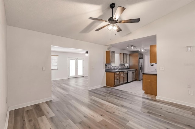 kitchen featuring vaulted ceiling, french doors, stainless steel refrigerator with ice dispenser, dark countertops, and open floor plan