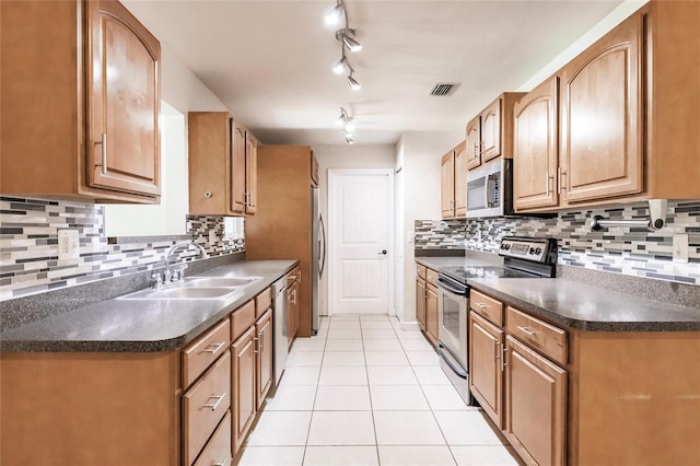 kitchen with dark countertops, light tile patterned flooring, appliances with stainless steel finishes, and a sink