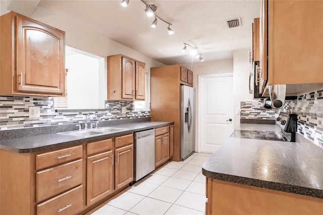 kitchen with a sink, stainless steel appliances, dark countertops, and visible vents