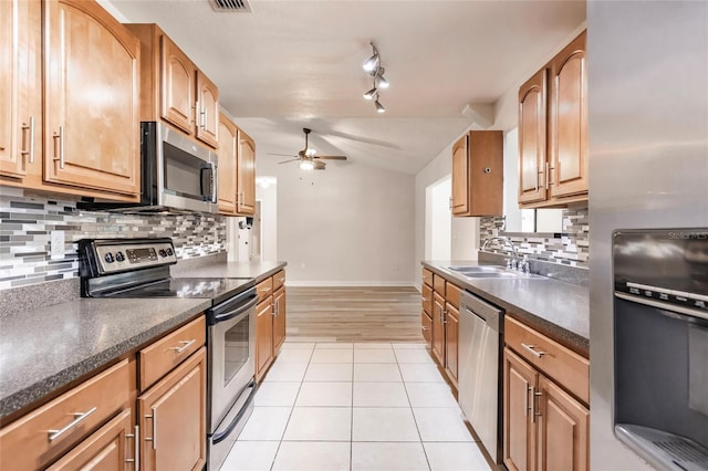 kitchen featuring a ceiling fan, a sink, appliances with stainless steel finishes, light tile patterned floors, and vaulted ceiling