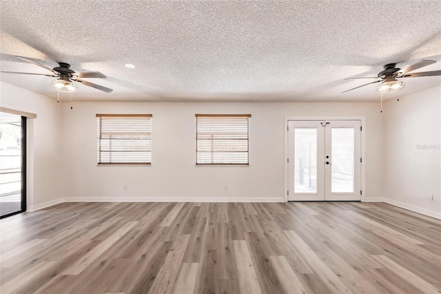 interior space featuring light wood-style flooring, plenty of natural light, french doors, and baseboards