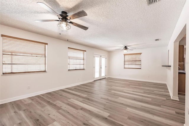 empty room with visible vents, light wood-style flooring, french doors, and baseboards