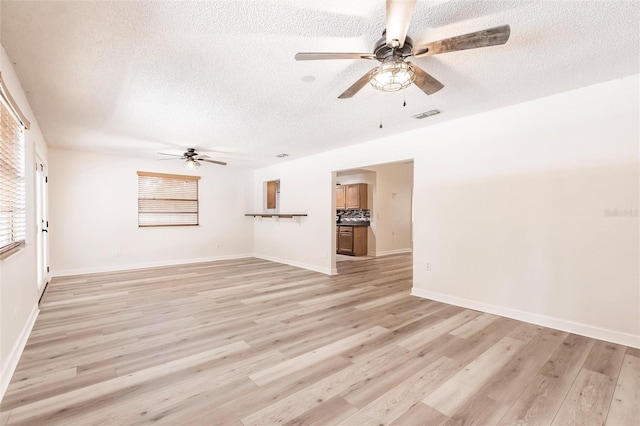 unfurnished room with light wood finished floors, visible vents, a healthy amount of sunlight, and a textured ceiling