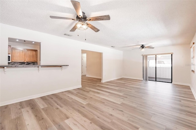 unfurnished living room featuring visible vents, light wood-style floors, and a textured ceiling