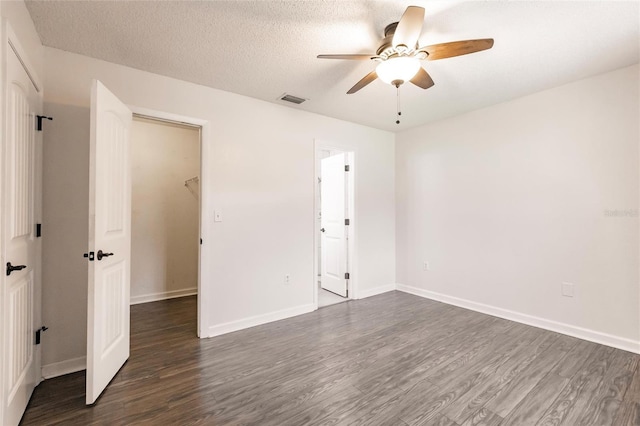 unfurnished bedroom with dark wood-style floors, visible vents, a textured ceiling, and baseboards