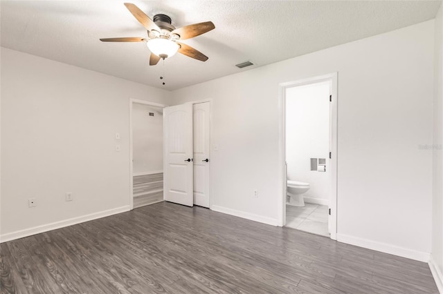 unfurnished bedroom with visible vents, ensuite bath, wood finished floors, and a textured ceiling