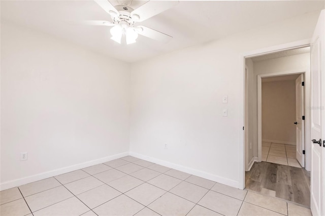 empty room with light tile patterned floors, baseboards, and ceiling fan