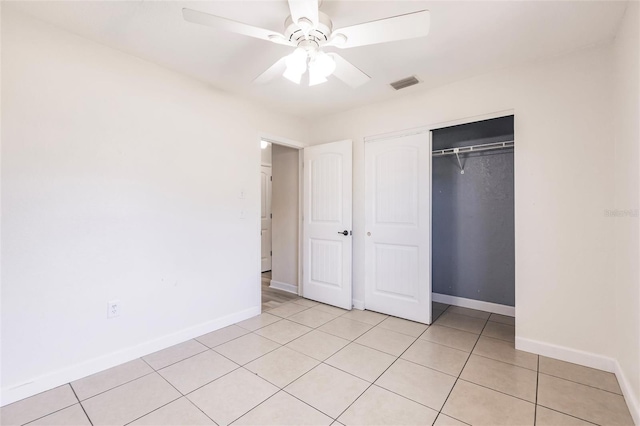 unfurnished bedroom featuring visible vents, a closet, light tile patterned floors, baseboards, and ceiling fan