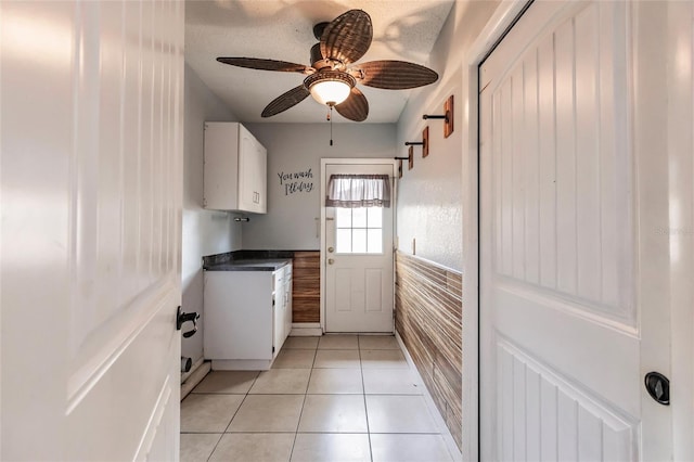 interior space featuring light tile patterned flooring, laundry area, and a ceiling fan