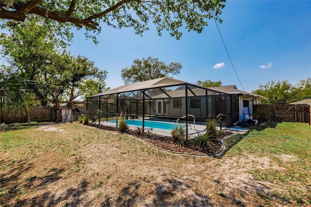 view of swimming pool with a lanai, a yard, and a fenced backyard