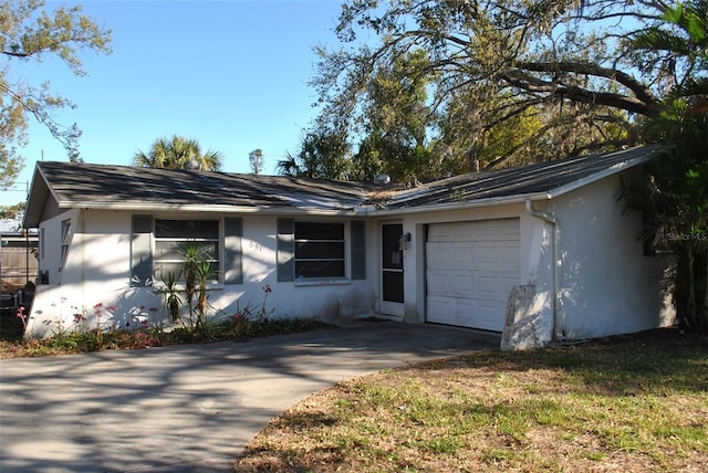 ranch-style home featuring driveway, an attached garage, and stucco siding