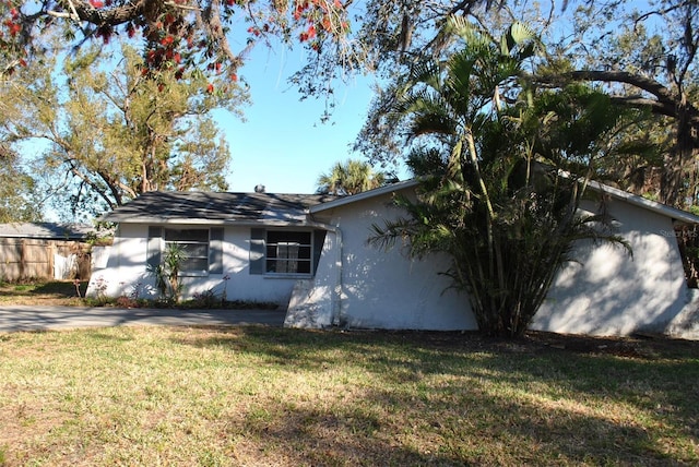 view of side of property with a yard, fence, and stucco siding