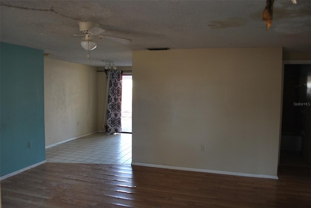 spare room with visible vents, baseboards, a ceiling fan, wood finished floors, and a textured ceiling