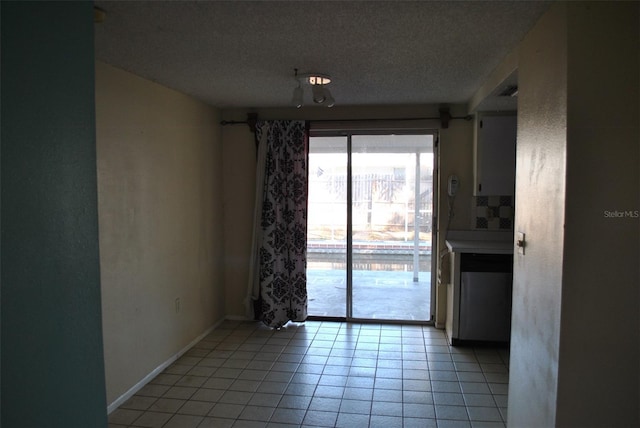 spare room with light tile patterned flooring, a textured ceiling, and baseboards