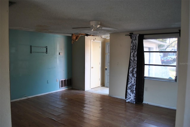 unfurnished room with visible vents, hardwood / wood-style floors, a ceiling fan, a textured ceiling, and baseboards