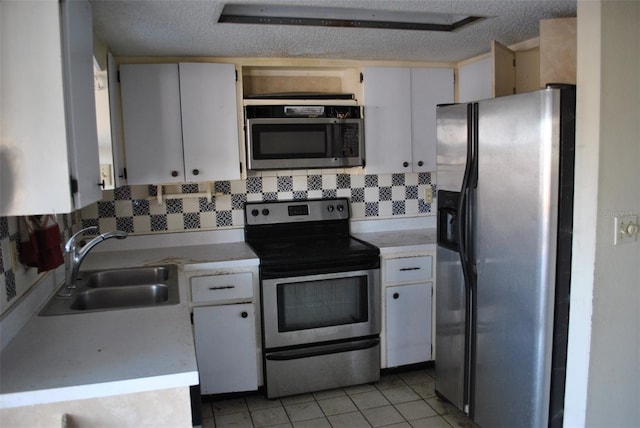 kitchen featuring light tile patterned floors, light countertops, appliances with stainless steel finishes, a sink, and a textured ceiling