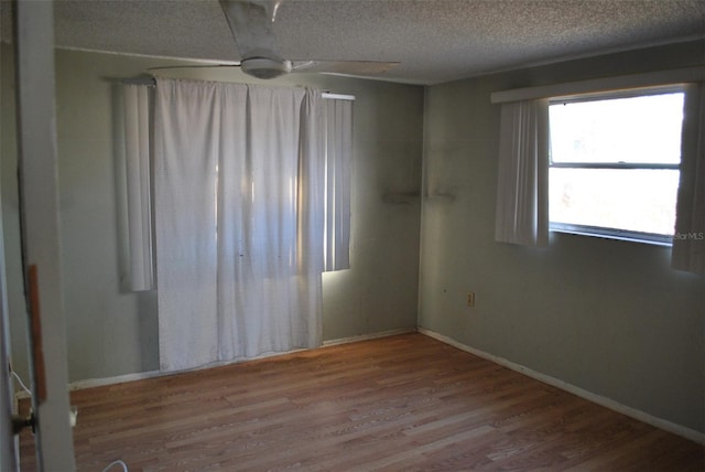 spare room with ceiling fan, a textured ceiling, baseboards, and wood finished floors