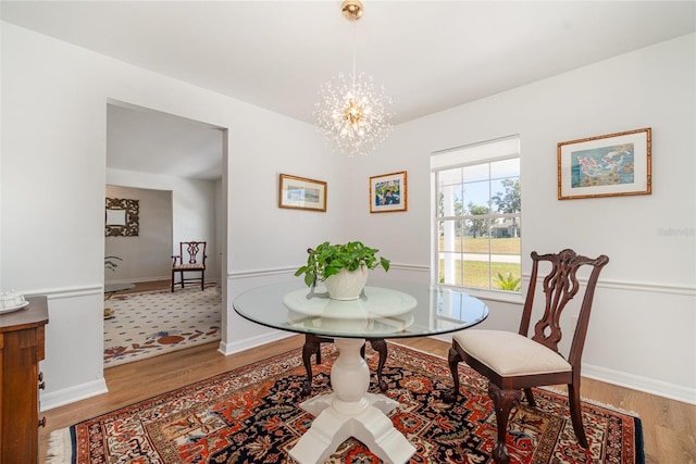 dining area with light wood finished floors, a chandelier, and baseboards