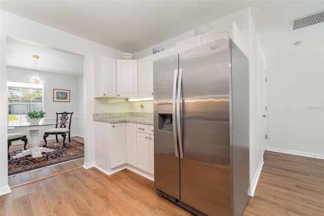 kitchen with visible vents, light stone countertops, stainless steel fridge with ice dispenser, light wood-type flooring, and white cabinets