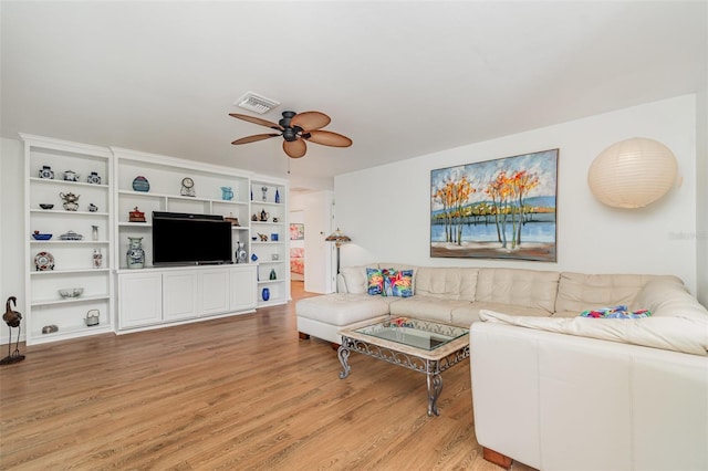 living room with visible vents, light wood-type flooring, and ceiling fan