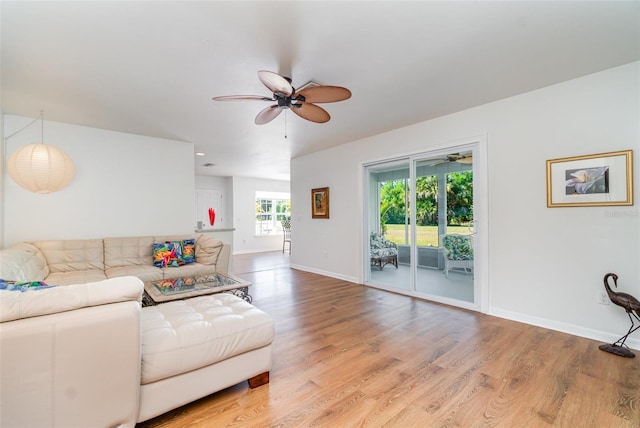 living area featuring baseboards, light wood finished floors, and ceiling fan