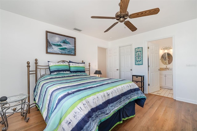 bedroom featuring wood finished floors, baseboards, visible vents, ceiling fan, and connected bathroom