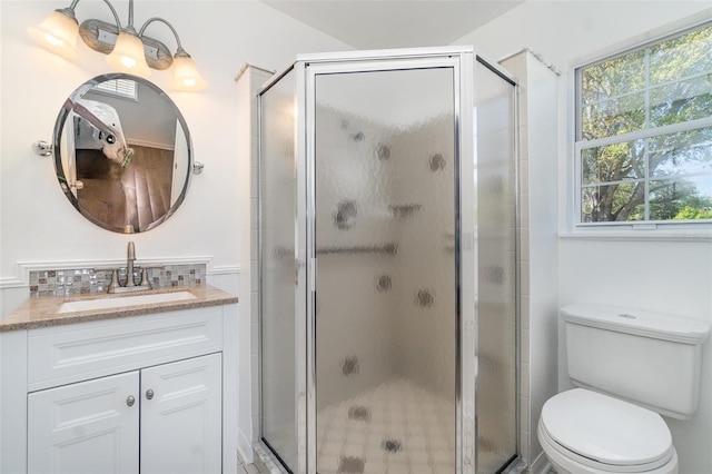 bathroom with a stall shower, toilet, and vanity