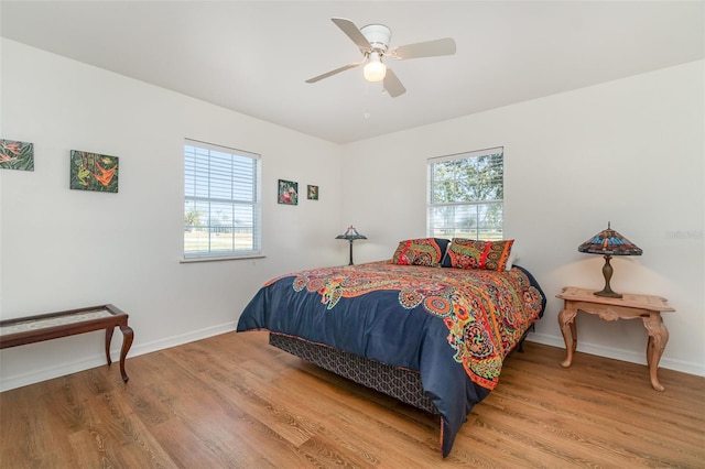 bedroom featuring multiple windows, baseboards, and wood finished floors