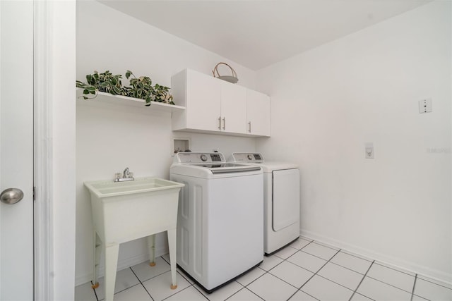 washroom featuring washer and dryer, a sink, cabinet space, light tile patterned flooring, and baseboards