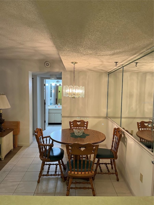 dining space featuring light tile patterned floors, a notable chandelier, and a textured ceiling