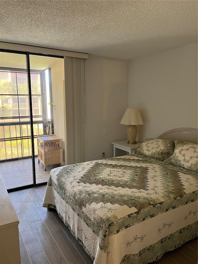 bedroom with a wall of windows, a textured ceiling, wood finished floors, and access to outside