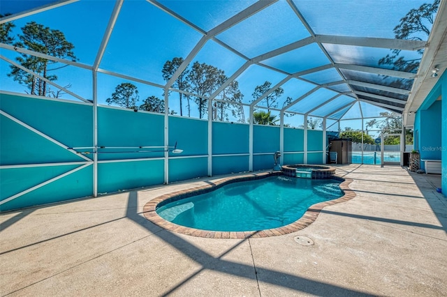 view of swimming pool featuring a patio area, glass enclosure, and a pool with connected hot tub