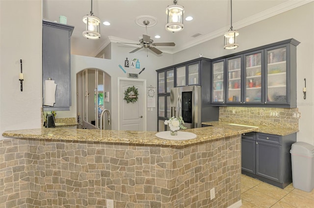 kitchen featuring light stone counters, visible vents, stainless steel fridge, and crown molding