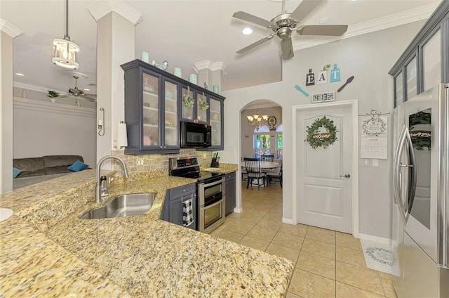 kitchen featuring ornamental molding, a sink, stainless steel appliances, arched walkways, and decorative backsplash