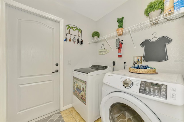 laundry room featuring light tile patterned floors, laundry area, and washing machine and dryer