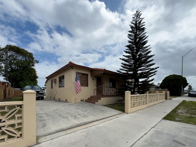 view of front of property with a fenced front yard, a tile roof, and stucco siding