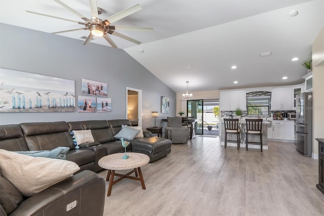 living room featuring recessed lighting, ceiling fan with notable chandelier, high vaulted ceiling, and light wood-style floors