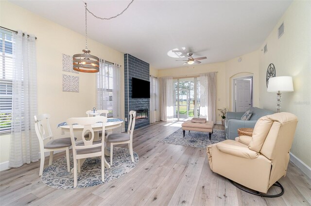 living room with baseboards, visible vents, ceiling fan, light wood-type flooring, and a large fireplace