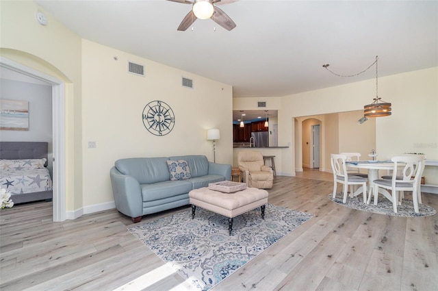 living room with arched walkways, visible vents, and light wood-style flooring