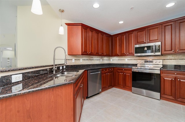 kitchen featuring a sink, decorative light fixtures, dark stone countertops, appliances with stainless steel finishes, and decorative backsplash