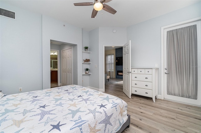 bedroom featuring wood finished floors, visible vents, baseboards, ensuite bath, and ceiling fan