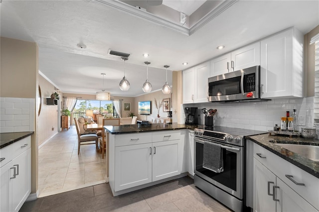 kitchen featuring visible vents, a peninsula, ornamental molding, stainless steel appliances, and white cabinets